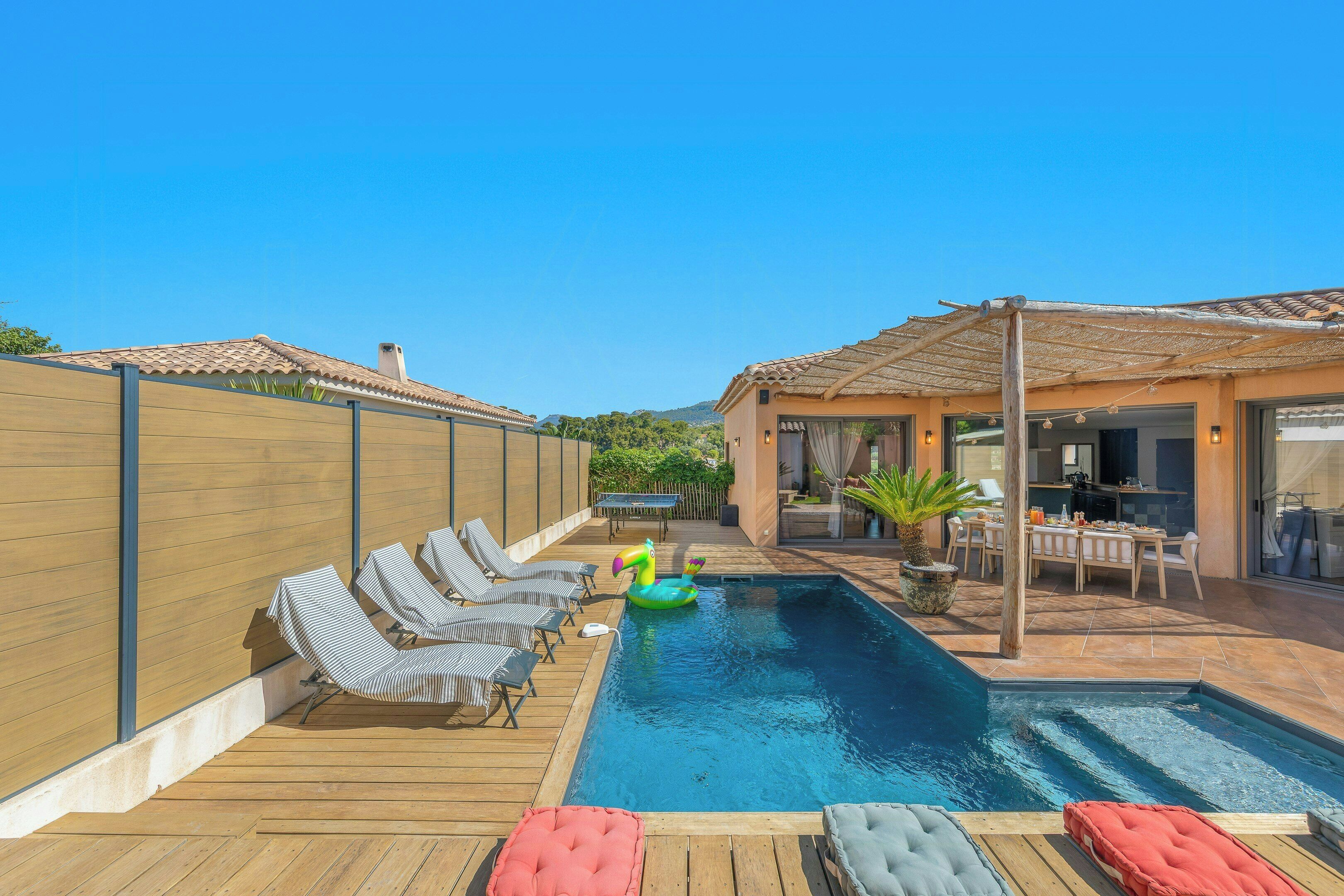 A swimming pool with lounge chairs and a dining area.