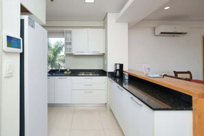 A modern kitchen with white cabinets, a black countertop, and an air conditioning unit. - Corporate Stays Edificio Pilar - N3A1 (Asunción)