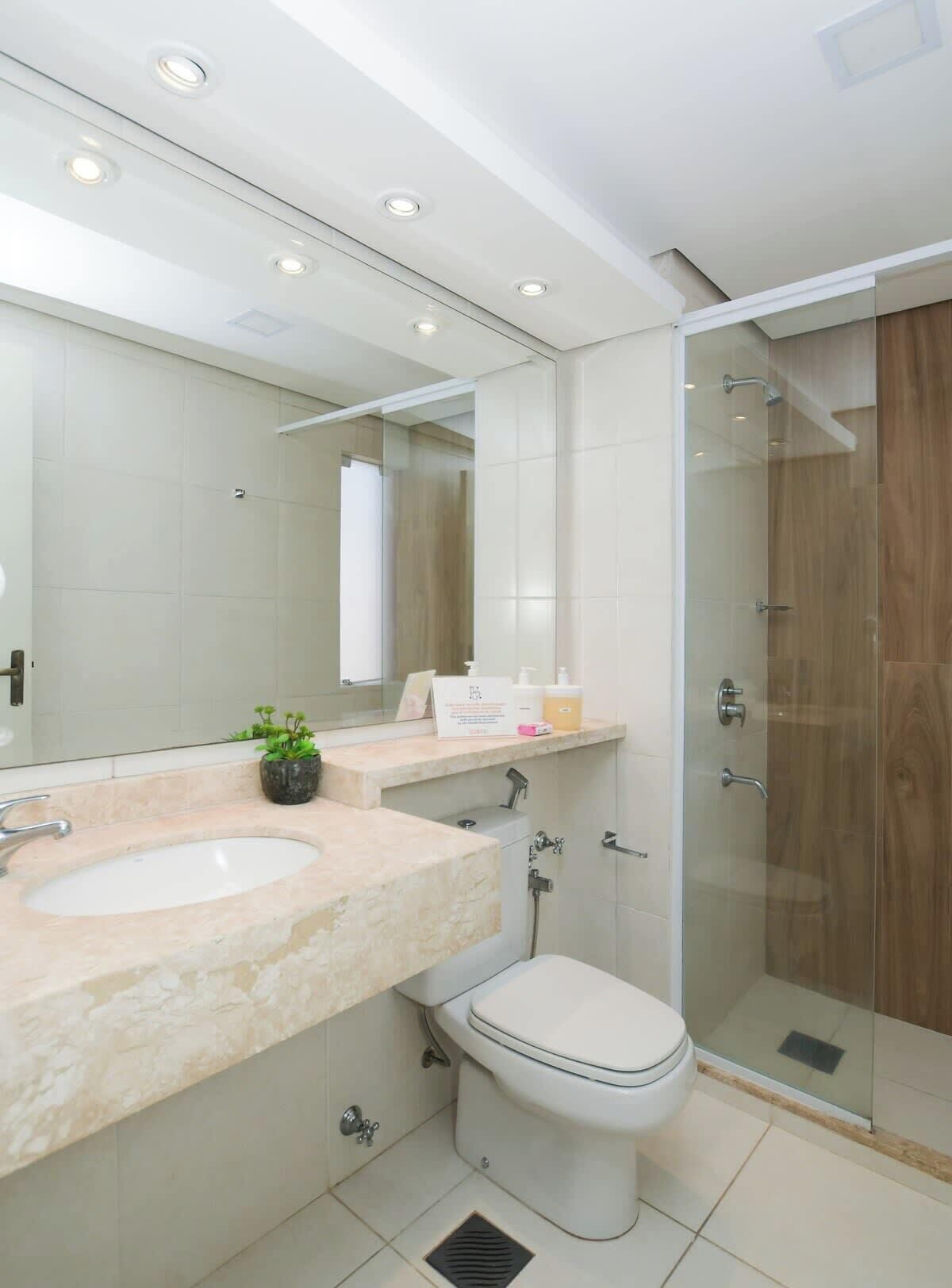 Un baño moderno con tocador doble lavamanos, inodoro y ducha con cerramiento de vidrio.
