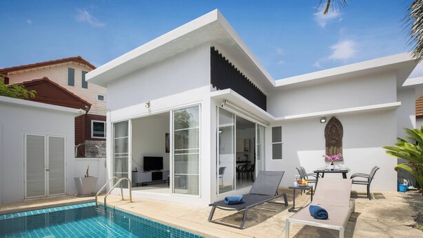 Et moderne hus med swimmingpool, en patio med liggestole og et spiseområde.