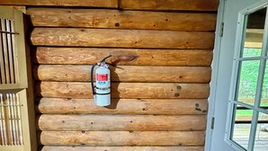 Interior de una cabaña de madera con un extintor colgado en la pared.