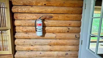 A wooden log cabin interior with a fire extinguisher mounted on the wall.