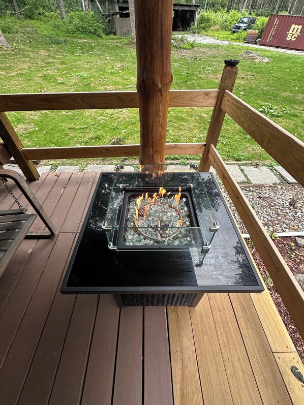 A wood deck with a glass-top fire pit.