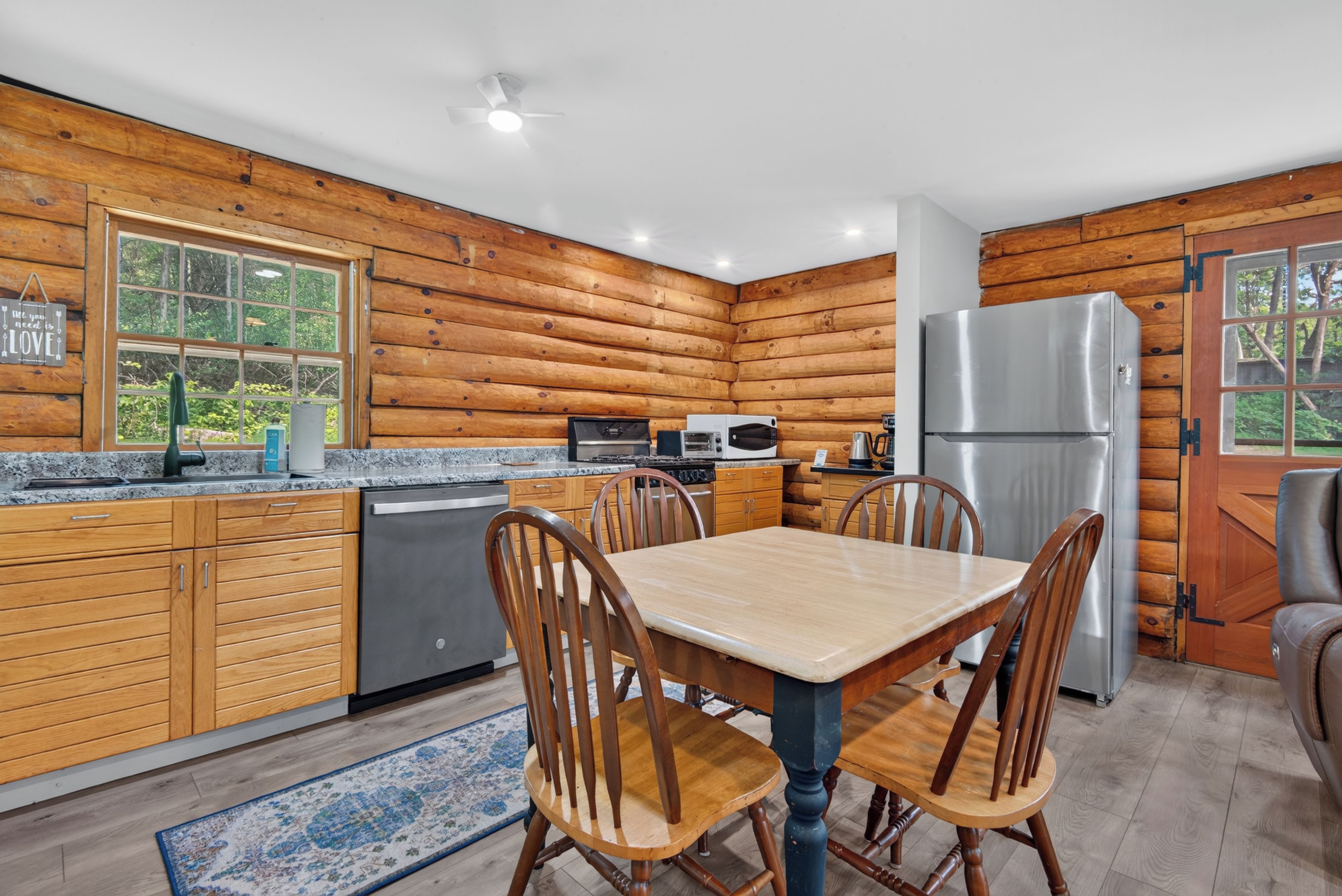 A modern kitchen with wooden walls, granite countertops, and stainless steel appliances.