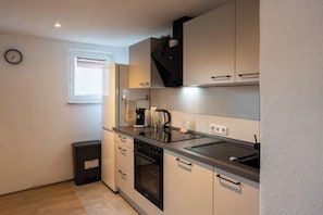 Een kleine keuken met een fornuis, oven en een modern aanrecht.