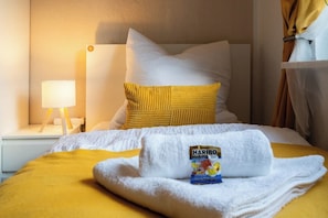 Een hotelkamer met een bed, nachtkastje, lamp en raam met gordijnen.