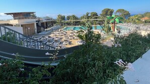 Un espace piscine aménagé sur le toit, avec des chaises longues, un restaurant et une vue sur l’océan.