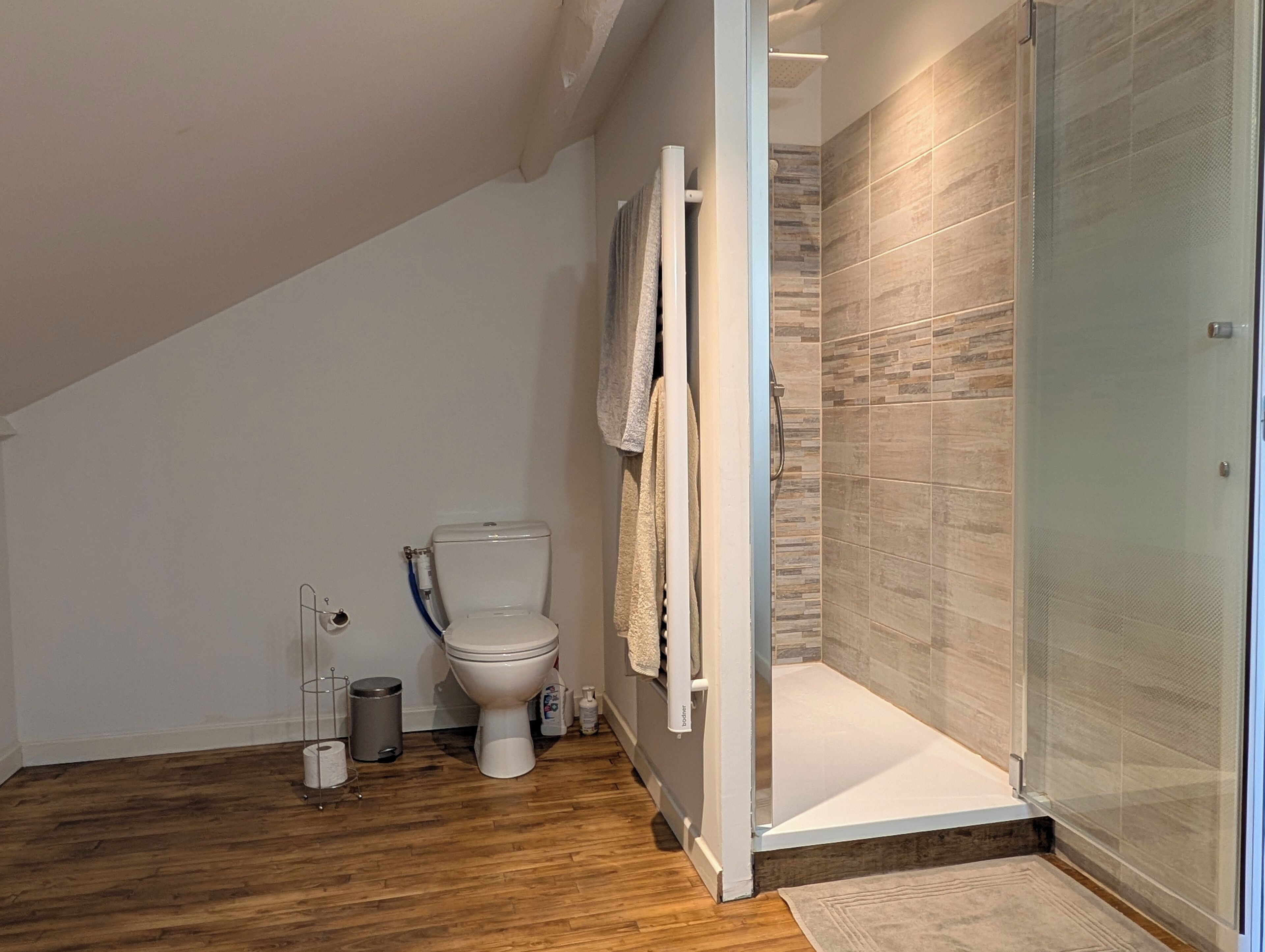 Une salle de bain moderne avec des toilettes, une douche et un plancher en bois.
