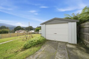 Een garage met gesloten deur, een gazon, een houten omheining en een heldere lucht.
