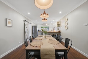 Un espace repas avec une longue table, des chaises et des luminaires suspendus.