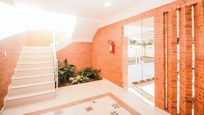 Eine Treppe führt zu einer zweiten Etage, ein Feuerlöscher ist an der Wand befestigt und ein Glastür-Eingang ist vorhanden.