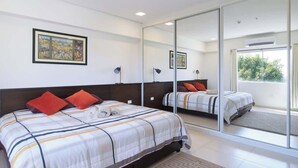 Ein Schlafzimmer mit einem großen Spiegel, einem Bett mit gestreifter Bettwäsche und einem gerahmten Bild an der Wand.