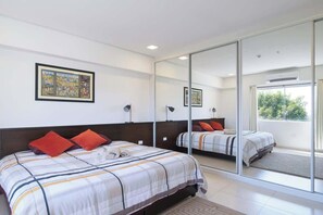 A bedroom with a large mirror, a bed with striped bedding, and a framed picture on the wall. - Corporate Stays Edificio Pilar - N3B (Asunción)