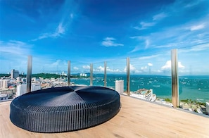 A high-rise room with a panoramic ocean view, a round black seating area, and large floor-to-ceiling windows. - Pattaya Central Excellent 1 Bed Room (Muang Pattaya)