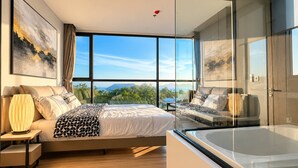 A modern bedroom with a large bed, a glass-enclosed shower, and a view of the outdoors. - Luxury Oceanfront Retreat Andromeda Apartment Pattaya (Pattaya City)