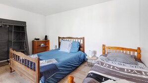 Ein Schlafzimmer mit einem hölzernen Bett, einem Nachttisch, einem Kleiderschrank und einem kleinen Regal mit Gegenständen.
