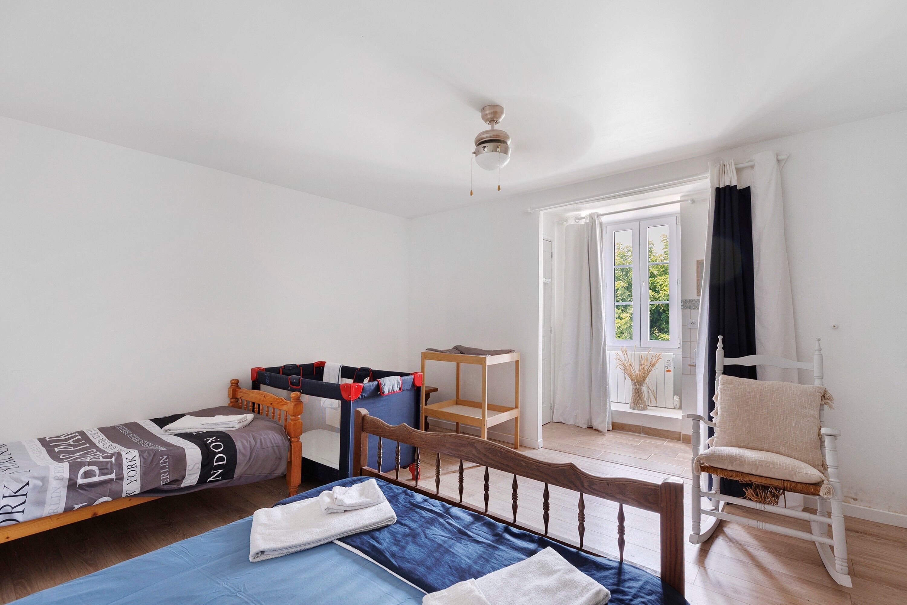 A room with a bed, a small table, a chair, and a window with curtains.