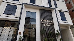 Um hotel com vários andares, fachada moderna, grandes janelas e uma placa indicando ser o Sdu Boutique Hotel.