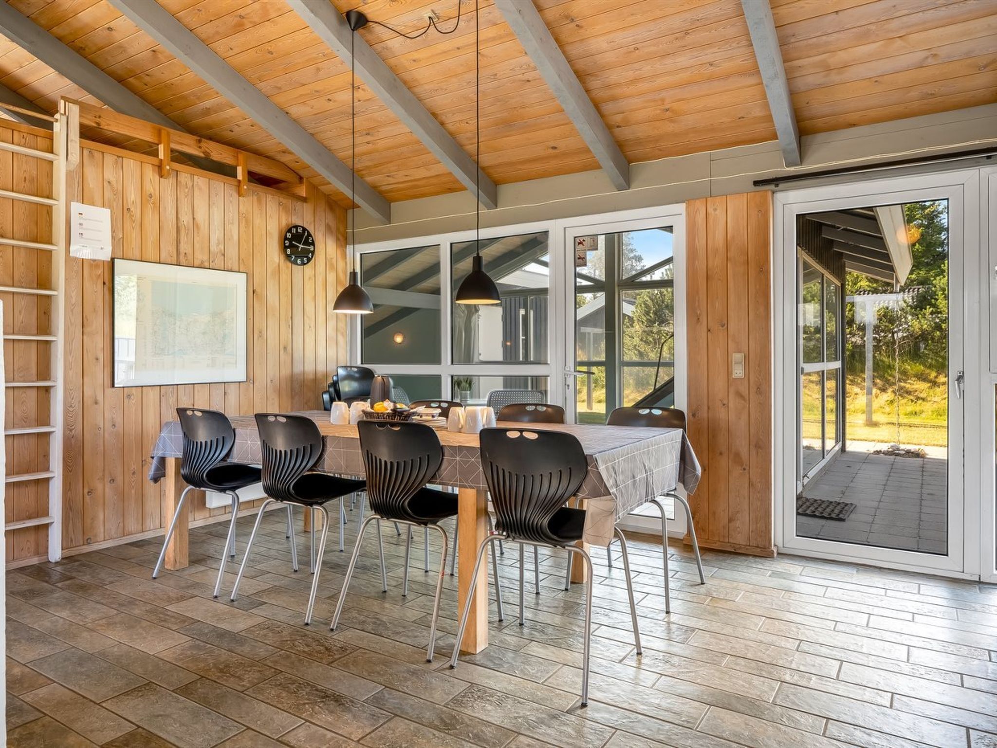 Una cucina moderna con pareti in legno, un'area pranzo con quattro sedie e ampie finestre.