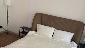 A bed with white bedding, a brown headboard, and a small bedside table with a lamp. - Beautiful 1-bedroom apartment in fantastic Poznań location (Poznań)