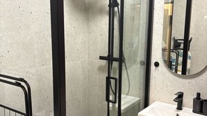 A modern bathroom with a glass-enclosed shower, a white sink, and a mirror above it. - Beautiful 1-bedroom apartment in fantastic Poznań location (Poznań)