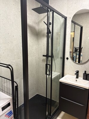 A modern bathroom with a glass-enclosed shower, a white sink, and a mirror above it. - Beautiful 1-bedroom apartment in fantastic Poznań location (Poznań)