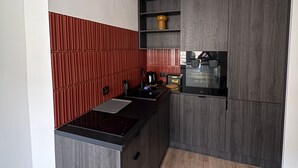 A compact kitchen with a black countertop, a built-in oven, and a red backsplash. - Beautiful 1-bedroom apartment in fantastic Poznań location (Poznań)