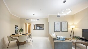 Een moderne woonkamer met een bank, een eettafel met stoelen, een televisie en kunst aan de muur.