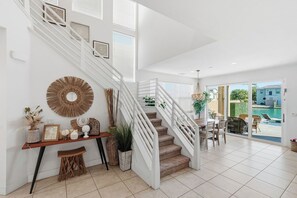 A staircase with white railings, a console table with decorative items, and a view of an outdoor swimming pool. - Lakefront Indio Luxury Tulum Vacation Home~Pool~Views. (Indio)