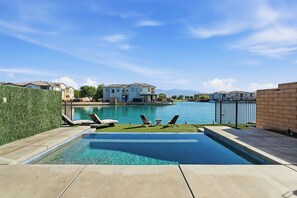 A swimming pool with lounge chairs, a view of residential buildings, and a clear sky. - Lakefront Indio Luxury Tulum Vacation Home~Pool~Views. (Indio)