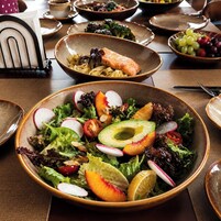 Una mesa de comedor con varios platos, incluyendo una ensalada, pasta y un plato de salmón.