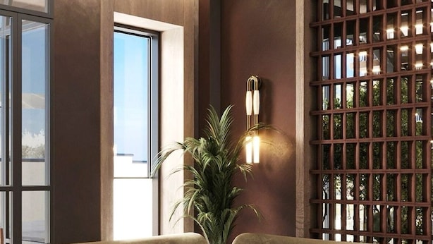 Una sala moderna con dos sofás, una mesita de centro, una planta en maceta y un aplique de pared.