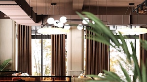 Un interior moderno con comedor, ventanas amplias y una planta.