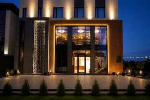 Un hotel moderno con fachada de vidrio, una escalera que conduce al piso superior y una entrada bien iluminada.