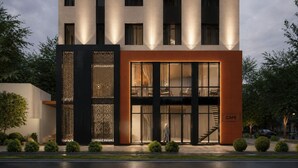 Un edificio moderno con una cafetería en la planta baja, amplias ventanas y un panel decorativo negro.