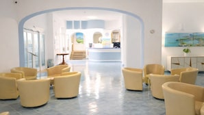 Un vestíbulo de hotel con mostrador de recepción, zona de estar y un amplio ventanal.