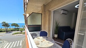 Een balkon met een tafel en stoelen, een uitzicht op de straat en een blik op het interieur.