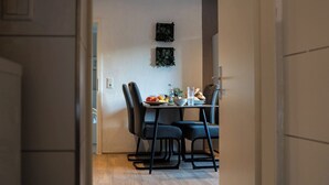 A dining area with a table set for two, chairs, a bowl of fruit, and a glass of water. - Shaft by Loftigo | Apartment with a wellness shower (Übach-Palenberg)