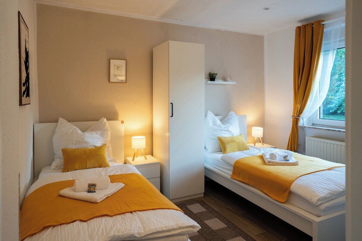 Une chambre d’hôtel avec deux lits, une armoire, une petite étagère et une fenêtre avec des rideaux.