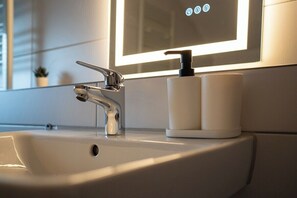 Un lavamanos de baño con un grifo moderno y un dispensador de jabón.