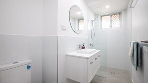 Ein modernes Badezimmer mit Waschbecken, Spiegel und Dusche.