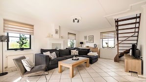 Ein Wohnzimmer mit einer Sofagarnitur, einem Couchtisch, einer TV-Kommode und einer Treppe.