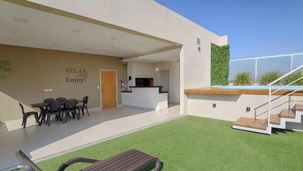 A modern building with a pool, outdoor seating, and a sign that reads 'RELAX chill Enjoy!' - Corporate Stays Edificio Pilar - N4A1 (Asunción)