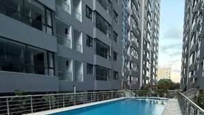 Una piscina con solárium de baldosas, rodeada de edificios residenciales altos.