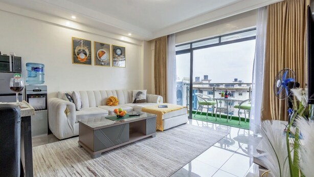 Un moderno salón con sofá, mesa de centro y vistas de la ciudad a través de amplias ventanas.