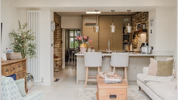 Een functionele leefruimte met kitchenette, een eethoek en een zithoek met een bank en stoelen.