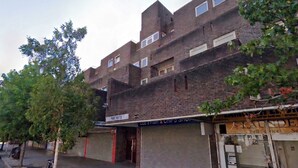 A multi-story brick building with closed shop fronts, including a visible 'PABE HOUSE' sign. - Refined 3BDR Retreat with Skyline Views (Greater London)