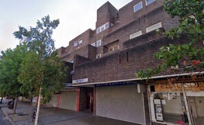 A multi-story brick building with closed shop fronts, including a visible 'PABE HOUSE' sign. - Refined 3BDR Retreat with Skyline Views (Greater London)