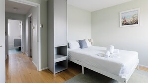 A bedroom with a bed, a wardrobe, a bathroom visible through an open door, and a framed picture on the wall. - Refined 3BDR Retreat with Skyline Views (Greater London)