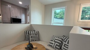 A modern kitchen with built-in cabinets, a round dining table, and a built-in bench with patterned cushions.